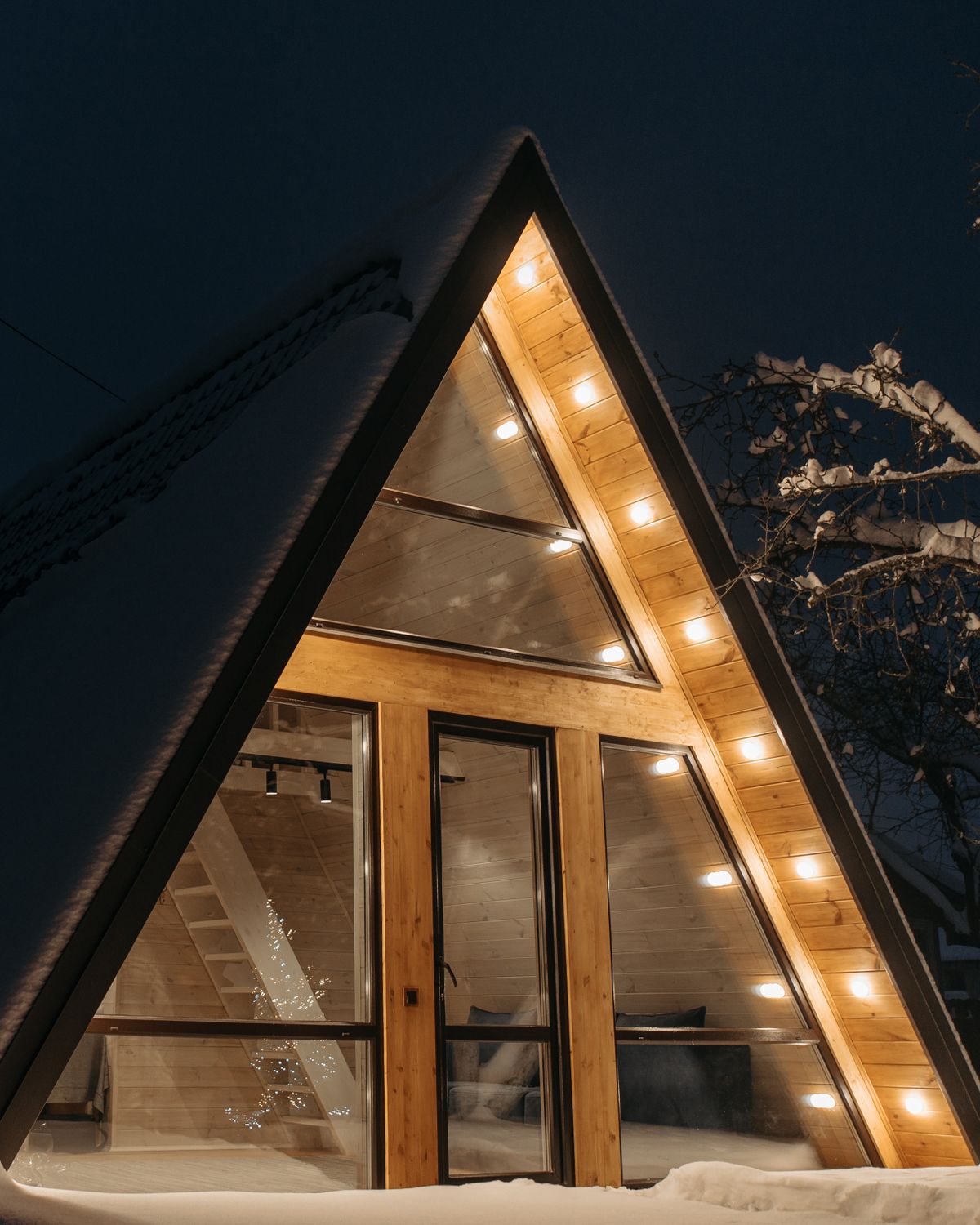 Chalet scandinave en bois pâle illuminé de lumières chaudes